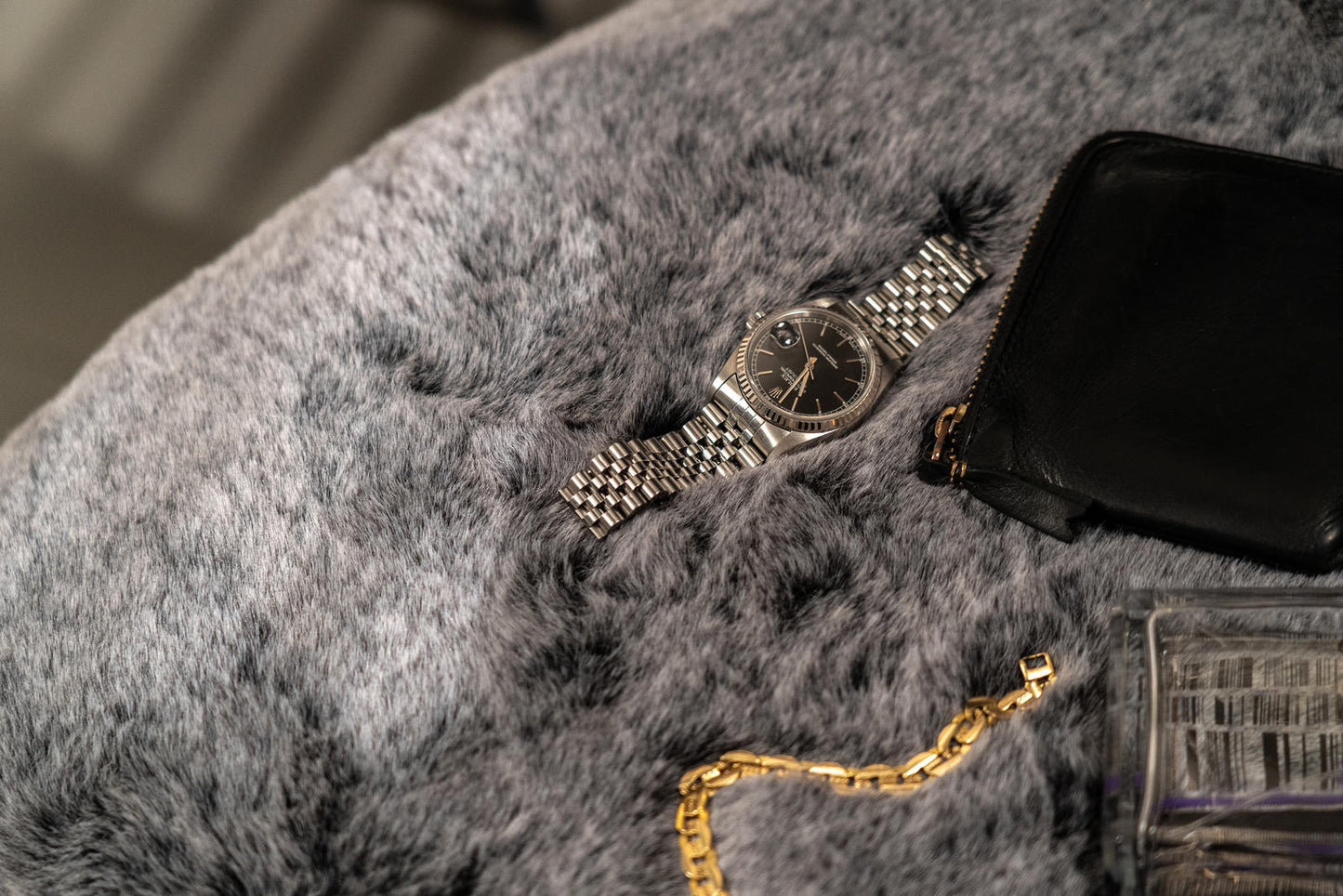 Sillón de pelo sintético gris y patas negro/oro.